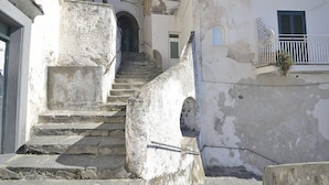 A narrow stone staircase leading to an entrance, flanked by weathered buildings with balconies and arched doorways. - Appartamento Attilia B: A graceful apartment which faces the sun and the sea, with Free WI-FI. (Amalfi)