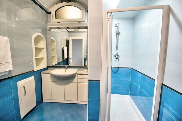 Une salle de bain avec un lavabo, un miroir et une douche.