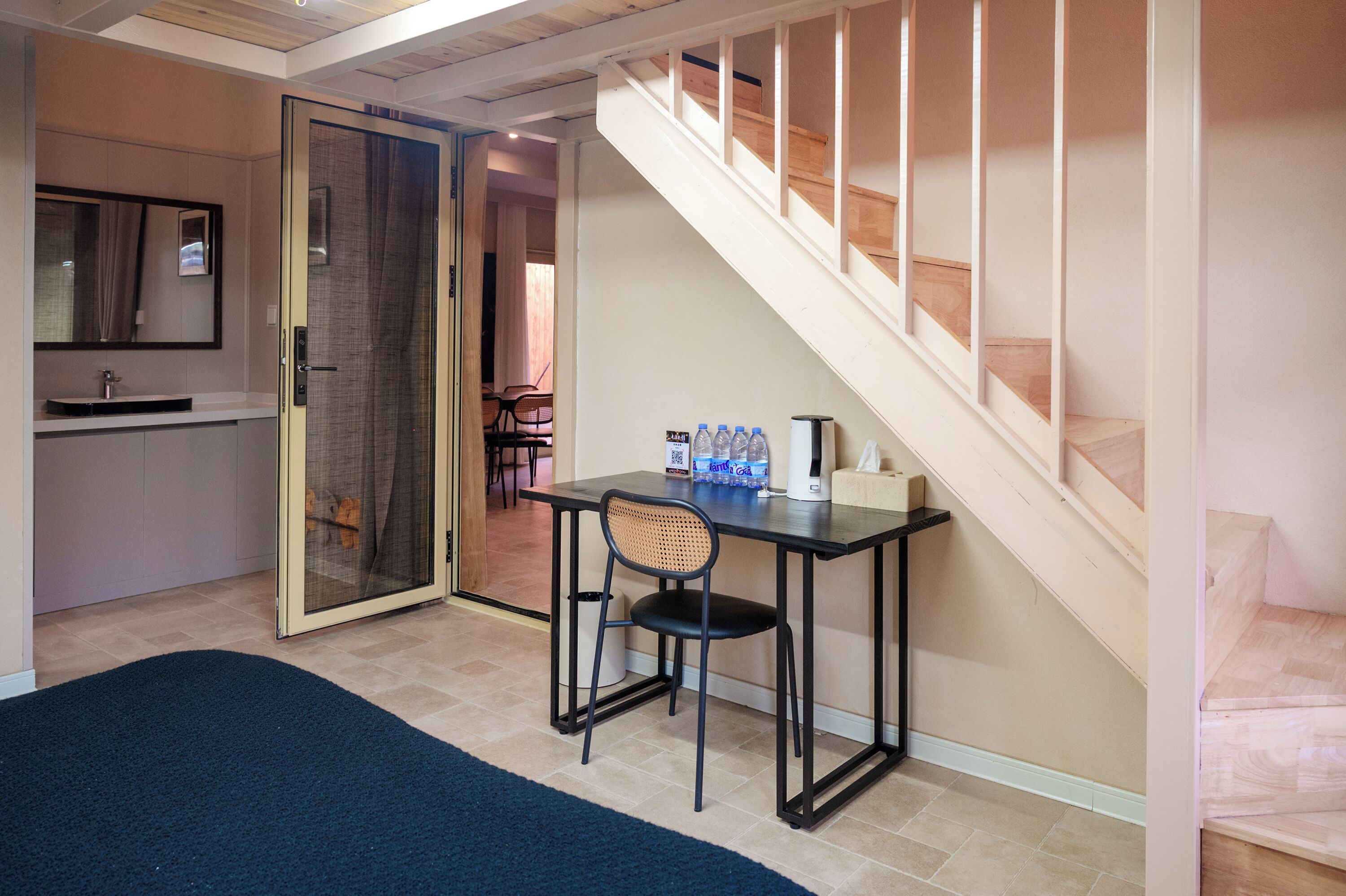 A room with a desk, chair, and a staircase.