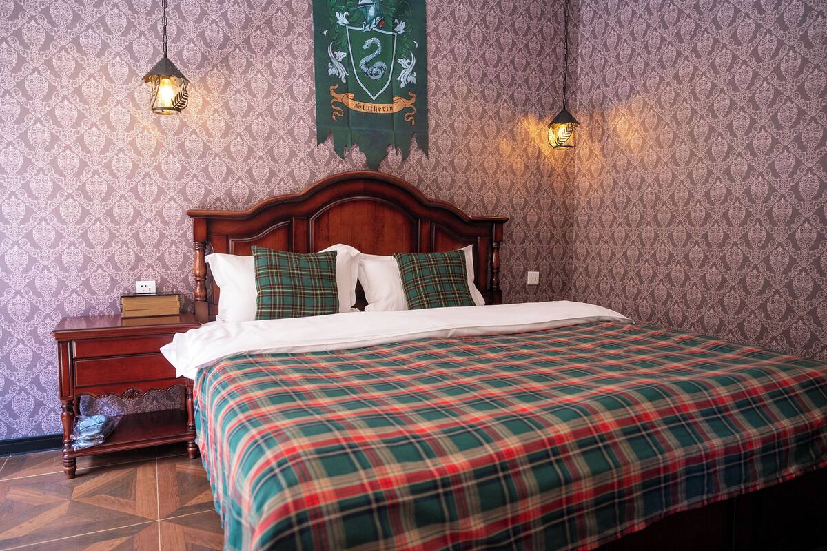 A neatly made bed with plaid bedding, a wooden headboard, and two wall-mounted lamps.