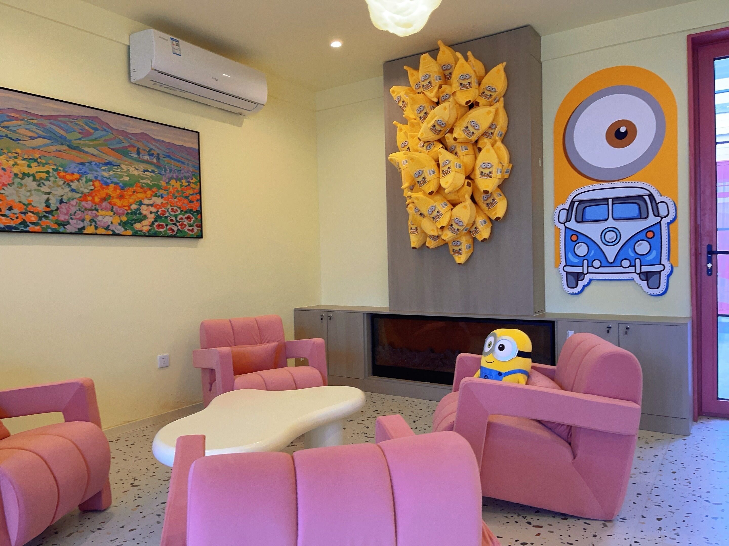 A room with pink furniture, a fireplace, a painting, and a Minion plush toy.
