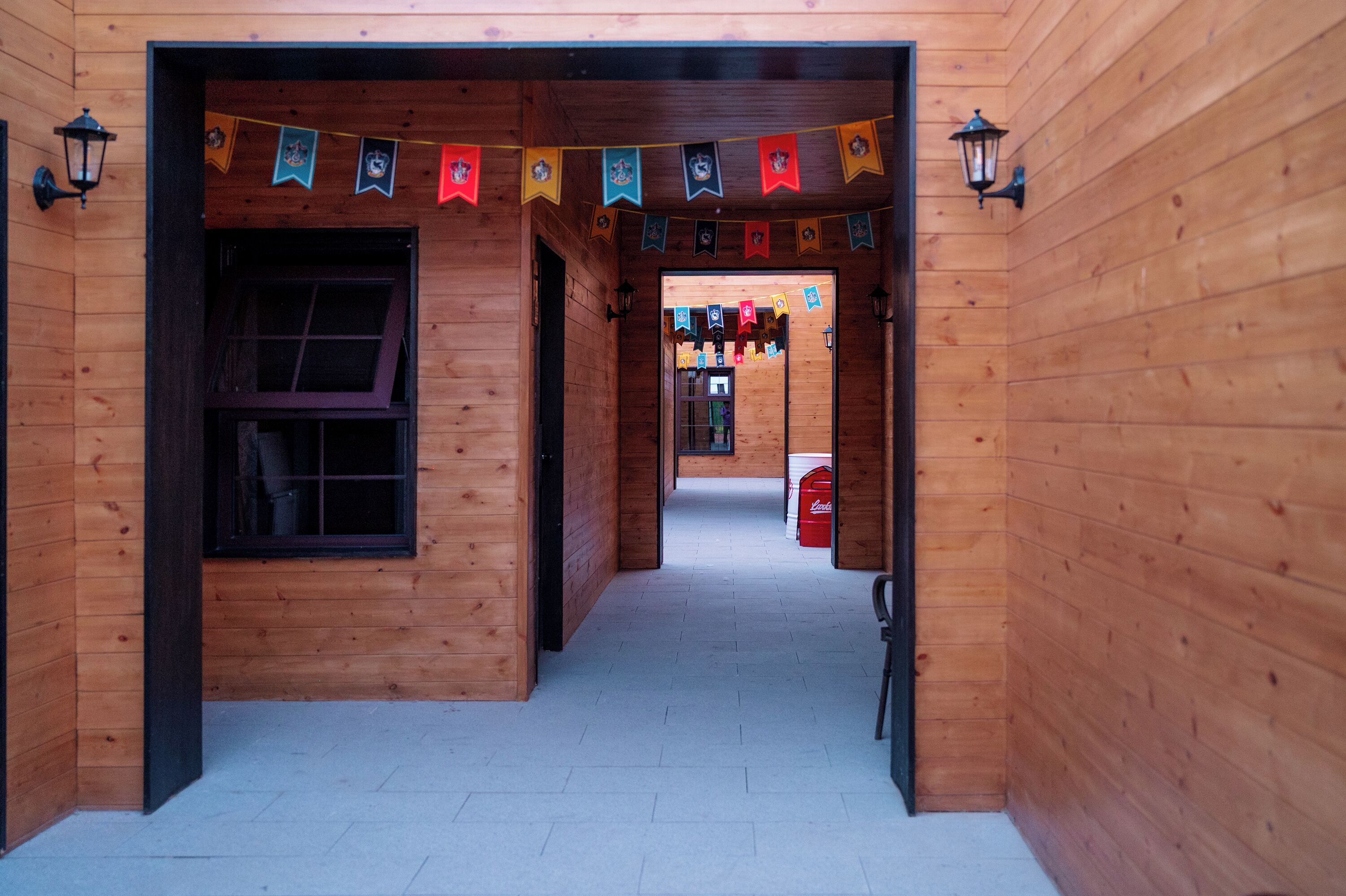 Un couloir en bois avec une fenêtre, des lanternes et un réfrigérateur Coca-Cola.