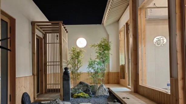 Un intérieur de style japonais traditionnel, avec des murs en bois, un sol recouvert de tatamis et un petit jardin de pierres.