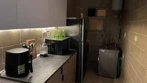 Eine kompakte Küche mit Kaffeemaschine, Kühlschrank und Wasserspender.