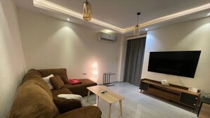 Ein modernes Wohnzimmer mit einem braunen Sofa, einem Couchtisch, einem Flachbildfernseher und einer Holz-Unterhaltungsanlage.