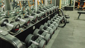 A row of dumbbells in a gym with a mirror reflecting the equipment. - Palmiers Hôtel Club (Errachidia)