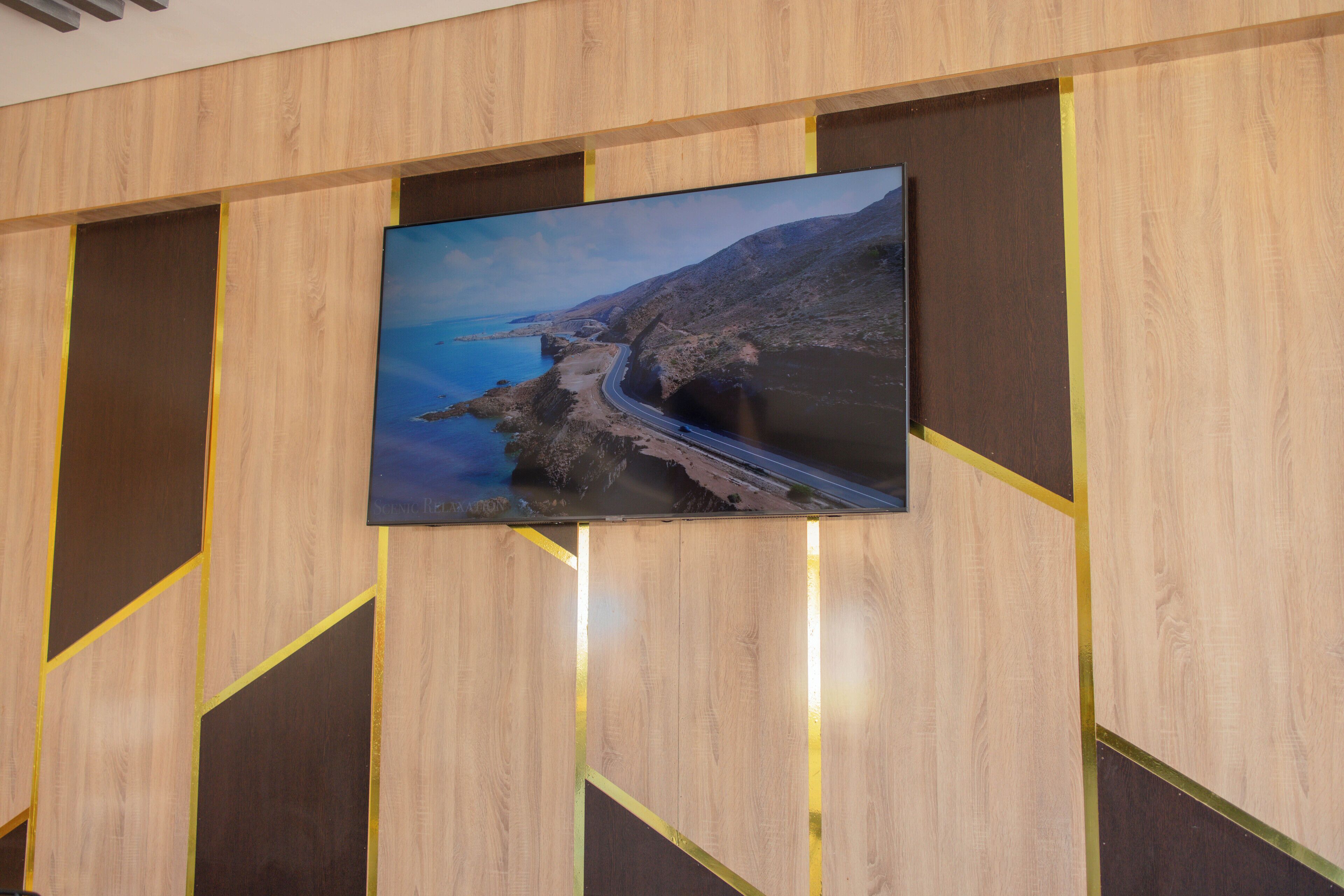 A flat-screen TV mounted on a wooden wall with geometric patterns.