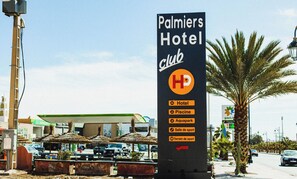 Señal de Palmier's Hotel Club que enumera sus servicios: hotel, cine, acuario, pabellón deportivo y campo de deportes.