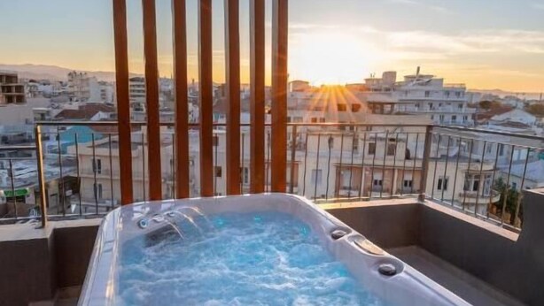 A hot tub on a balcony with a city view. - Anele Luxury Suites (Chania)