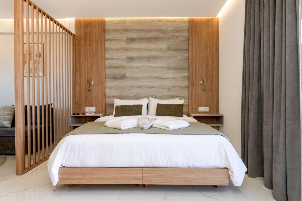 Un dormitorio moderno con cabecera de madera, una cama con ropa blanca y una mesita de noche.