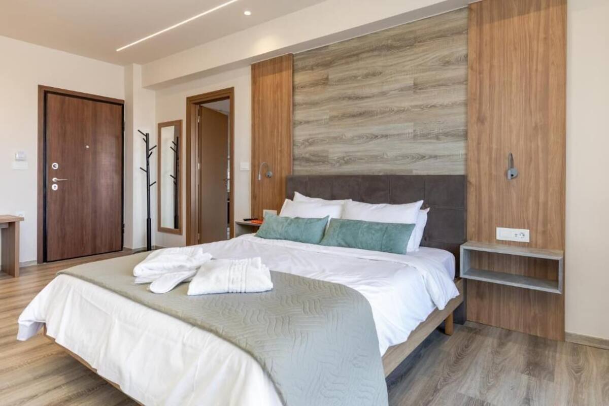 Une chambre moderne avec un grand lit, une tête de lit en bois et une étagère intégrée.