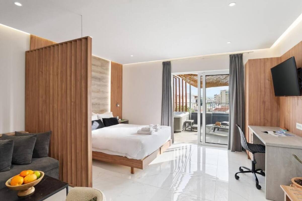 Une chambre d’hôtel moderne, équipée d’un lit, d’un bureau et offrant une vue à travers une porte vitrée.