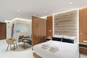 A modern hotel room with a bed, a desk, a chair, and a glass partition.
