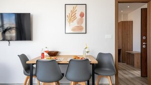 A dining area with a table, chairs, and a framed artwork on the wall. - Anele Luxury Suites (Chania)