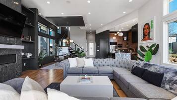 A modern living room with a grey sectional sofa, a white coffee table, and a fireplace.