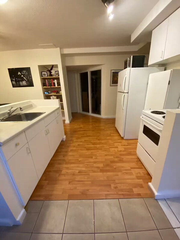 Una cocina con armarios blancos, un lavamanos, una estufa y un refrigerador.