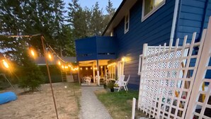 A pathway leading to a house with a blue exterior, a white lattice fence, and string lights.