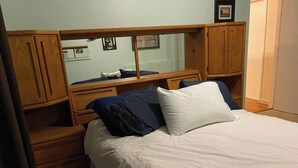 A bedroom with a bed, wooden headboard, and a nightstand.