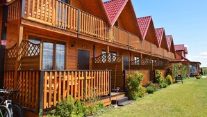 Een rij houten vakantiehuisjes met rode daken, balkons en een gazon.