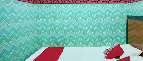 A bed with red and white bedding, a patterned wall, and a decorative border.