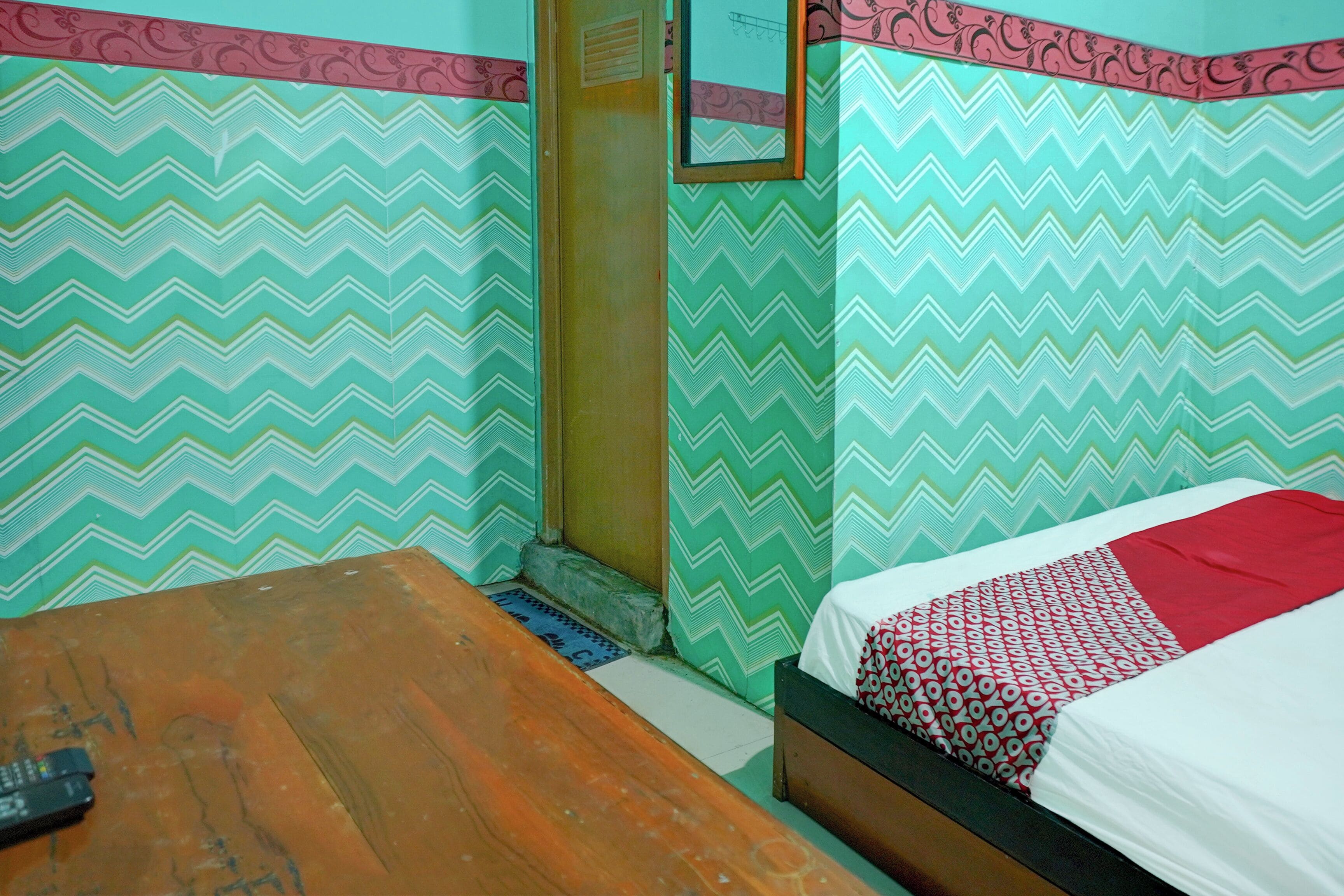 A room with a bed, a wooden table, and a patterned wall.
