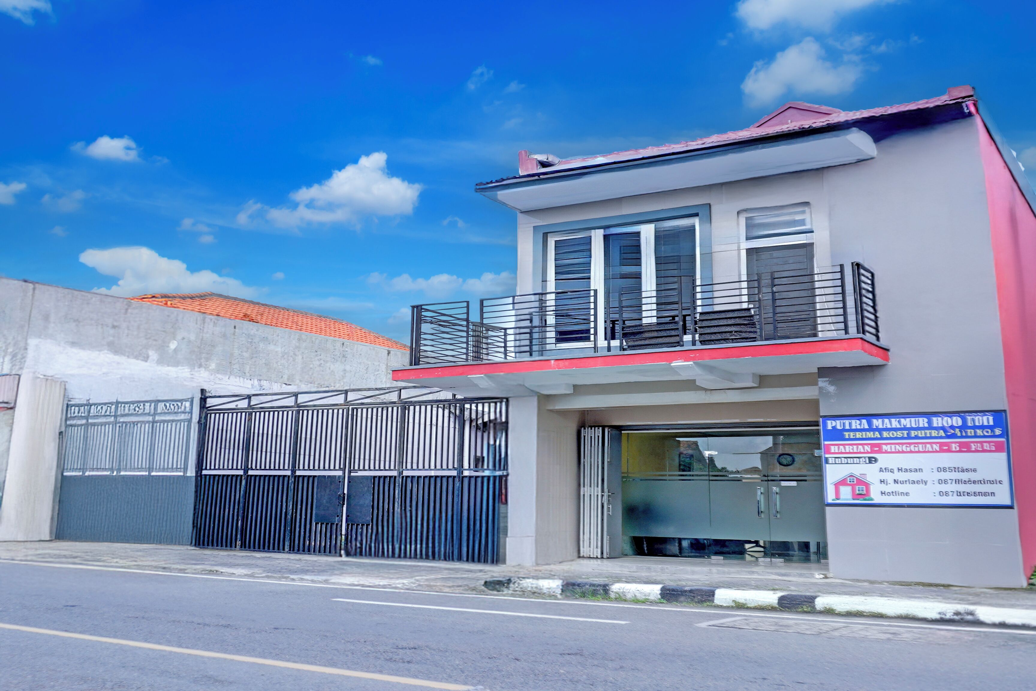 A two-story building with a balcony, a gated entrance, and a signboard.