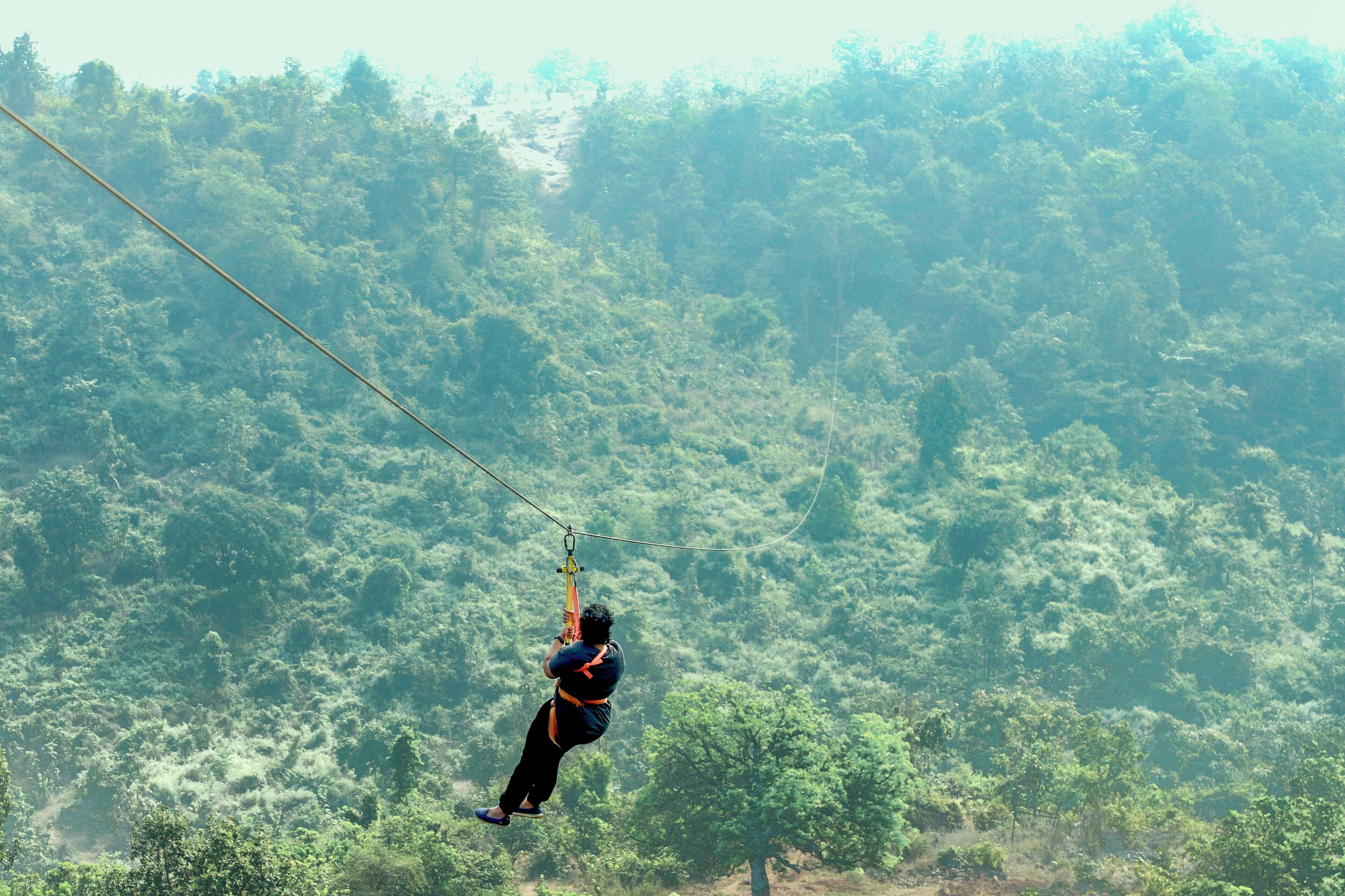 A person zip-lining through a forested area.