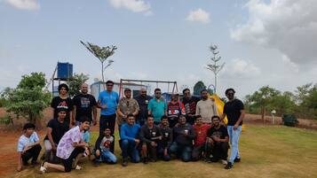 Um grupo de pessoas posando em ambiente externo, com um parquinho e um edifício ao fundo.