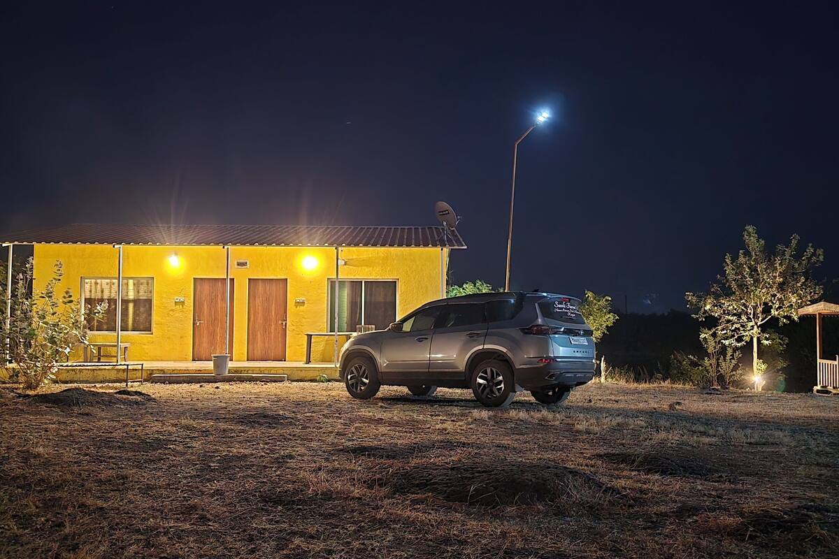 Een voertuig geparkeerd voor een geel gebouw met meerdere deuren en een schotelantenne.