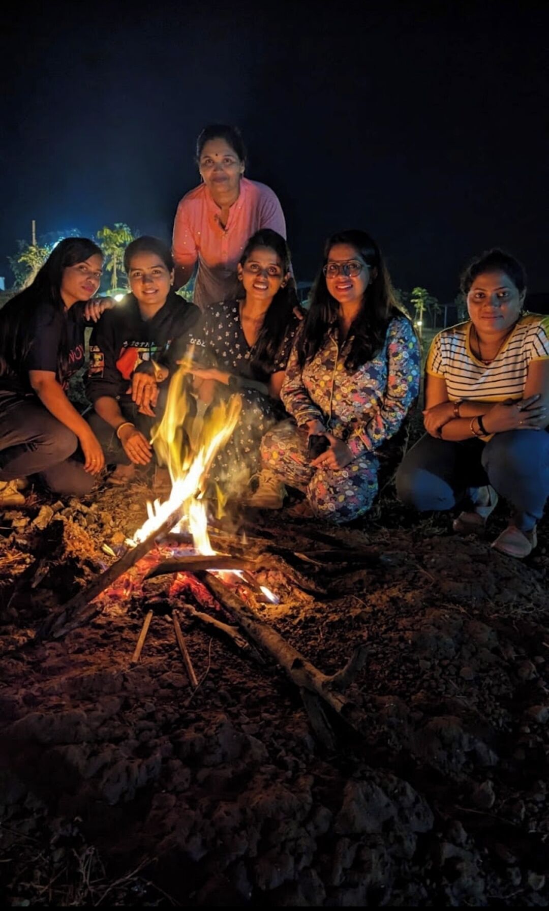 Eine Gruppe von Menschen versammelt sich nachts um ein Lagerfeuer.