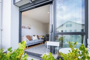 A modern interior with a sofa, a small table, and a glass door leading outside.
