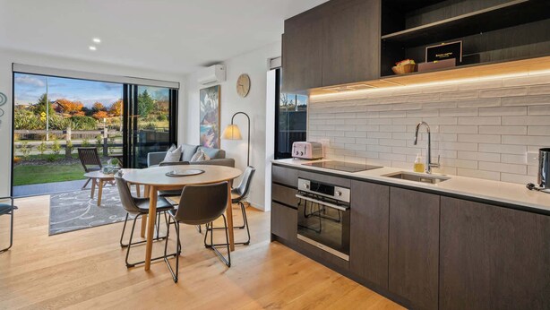 Een moderne keuken met een inbouwoven, een spoelbak en een eethoek met een ronde tafel en stoelen.