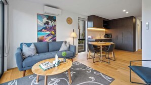 Een moderne woonkamer met een bank, salontafel en eethoek.