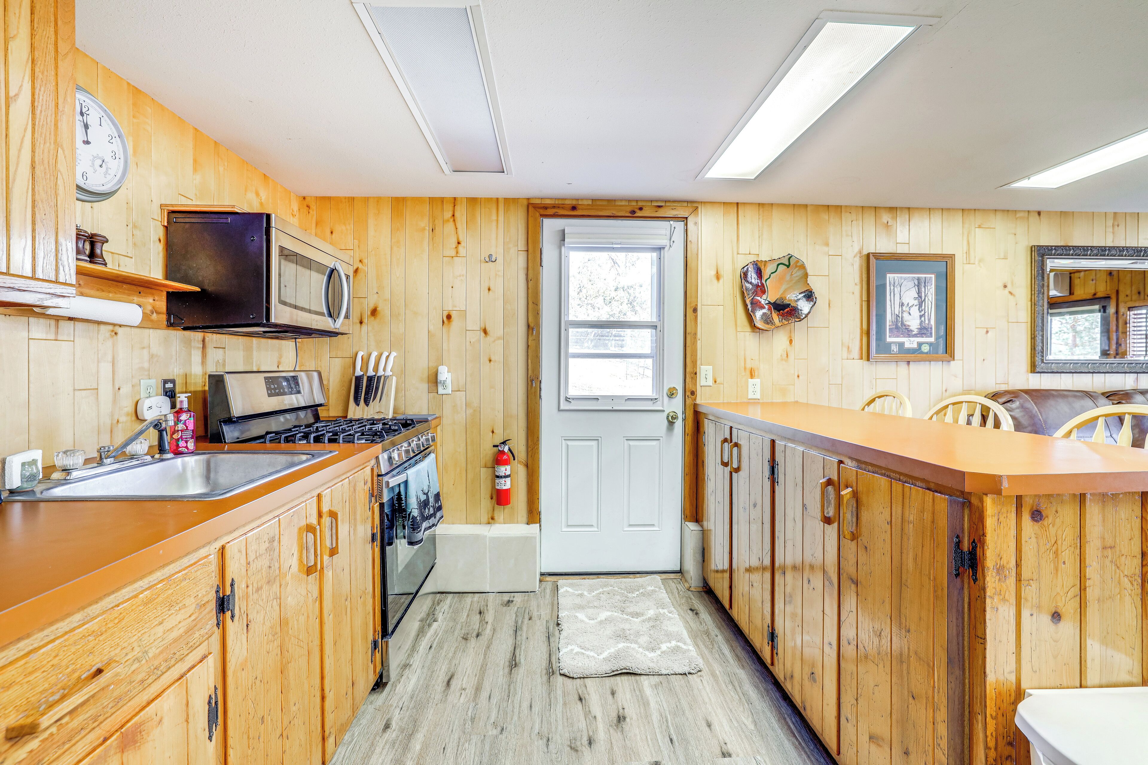 A kitchen with wooden cabinets, a microwave, a stove, and a sink.