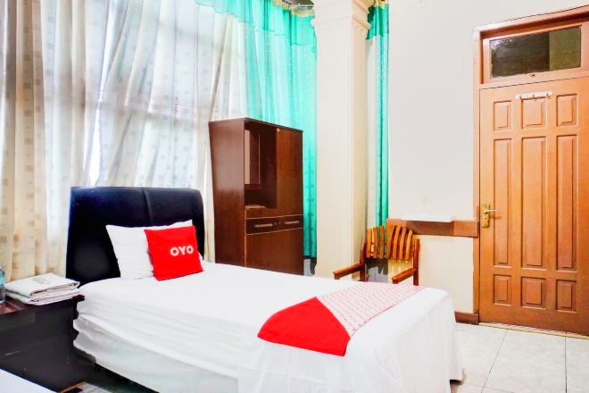 Una habitación de hotel con cama, escritorio, silla, armario y puerta.
