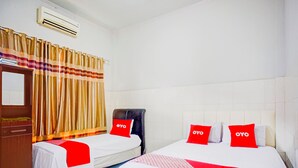 Habitación de hotel con dos camas, un armario, un espejo y una cortina.