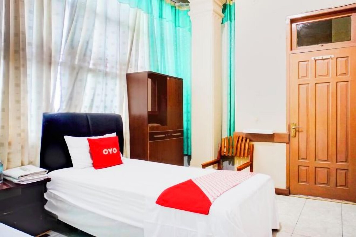 Una habitación de hotel con cama, escritorio, armario y puerta.