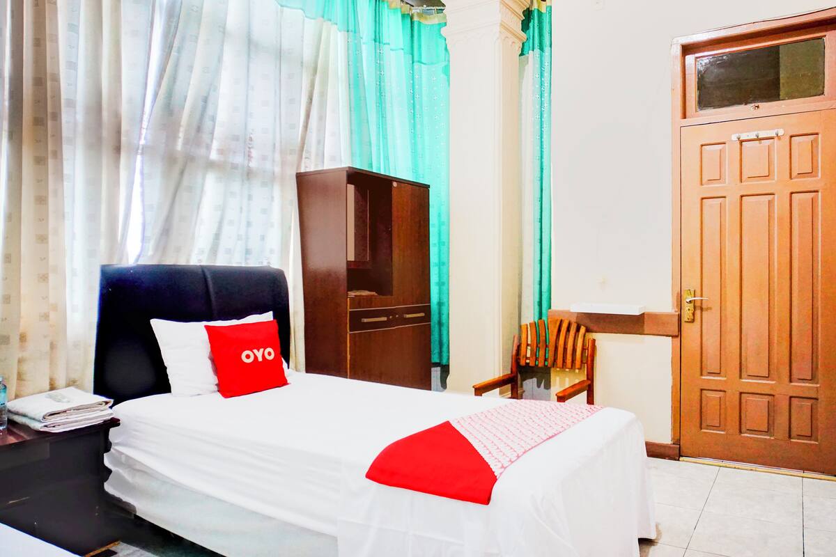 Una habitació d'hotel amb llit, un armari de fusta, un escriptori amb cadira i una porta.