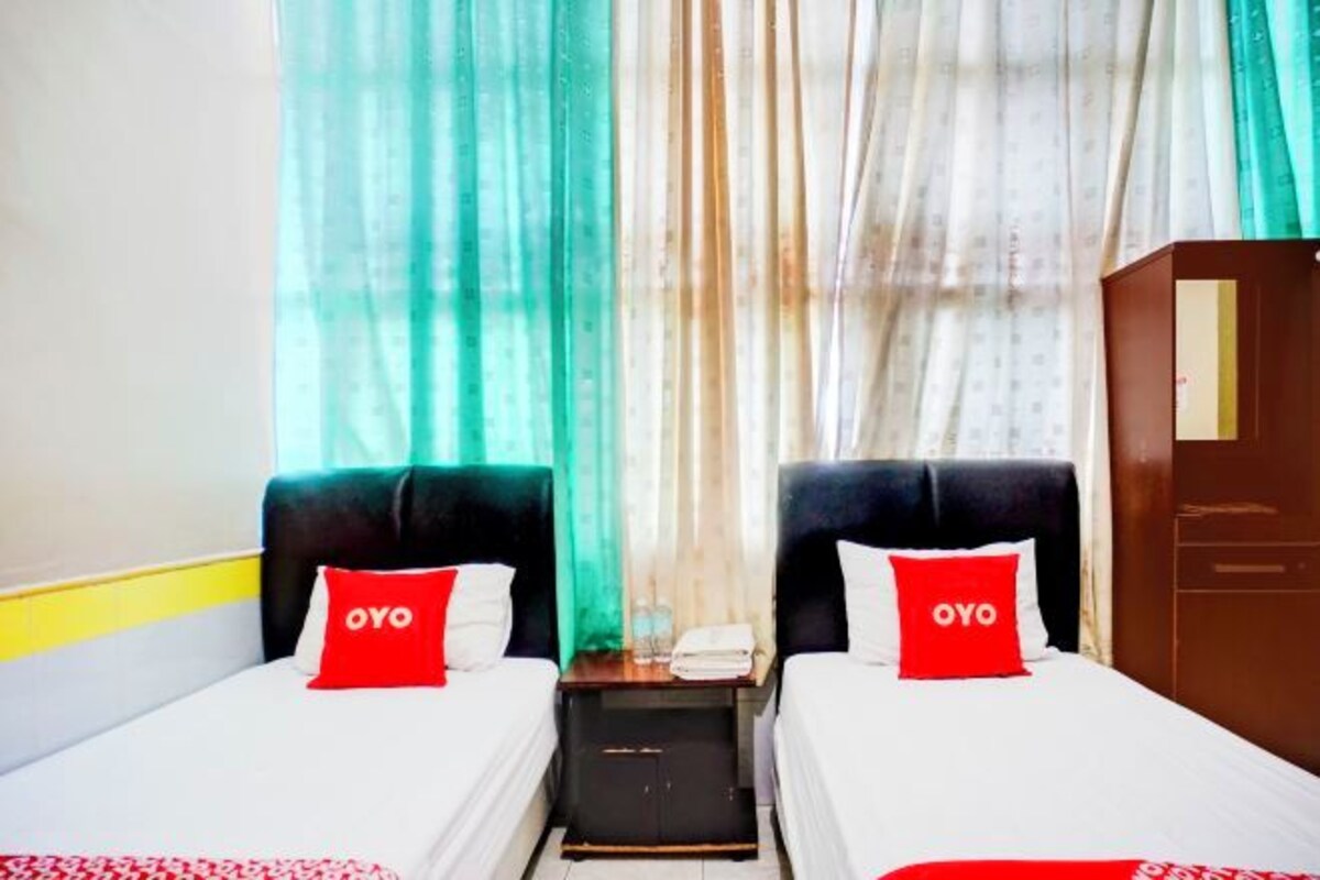 Habitación de hotel con dos camas, cada una con un almohadón rojo que dice "OYO".