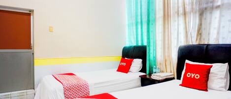 A hotel room with two beds, each with a red and white patterned bedspread and pillows labeled "OYO".