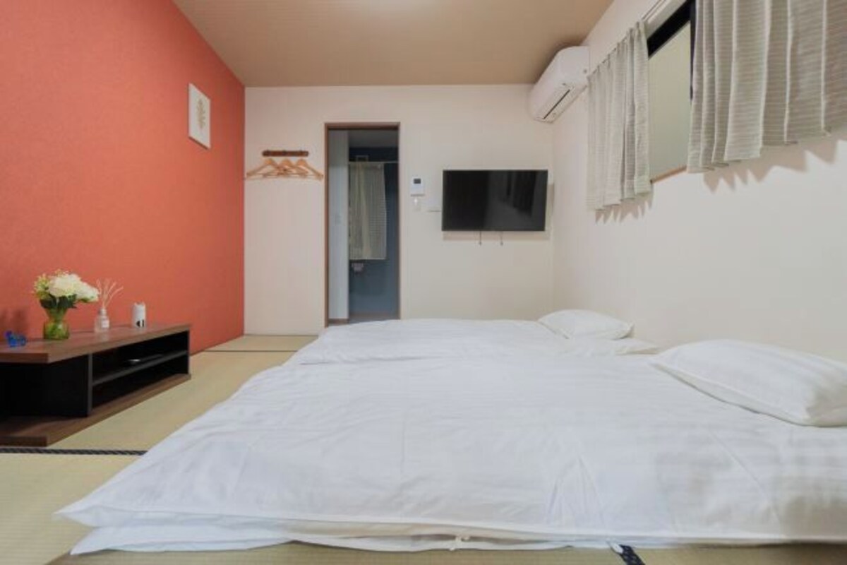 A room with a bed, a television, and a small table with flowers.