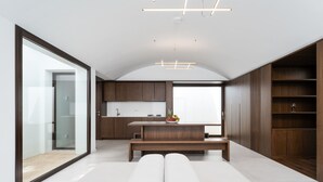 A modern interior with a kitchen, dining area, and built-in wooden shelving. - Villa 'Domo La Vela' with Sea View, Wi-Fi and Air Conditioning (Orosei)