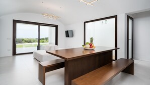 A modern kitchen with a wooden table, a fruit bowl, and a TV on the wall. - Villa 'Domo La Vela' with Sea View, Wi-Fi and Air Conditioning (Orosei)