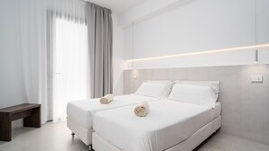 A modern hotel room with two beds, a bench, and a large window with curtains. - Villa 'Domo La Vela' with Sea View, Wi-Fi and Air Conditioning (Orosei)
