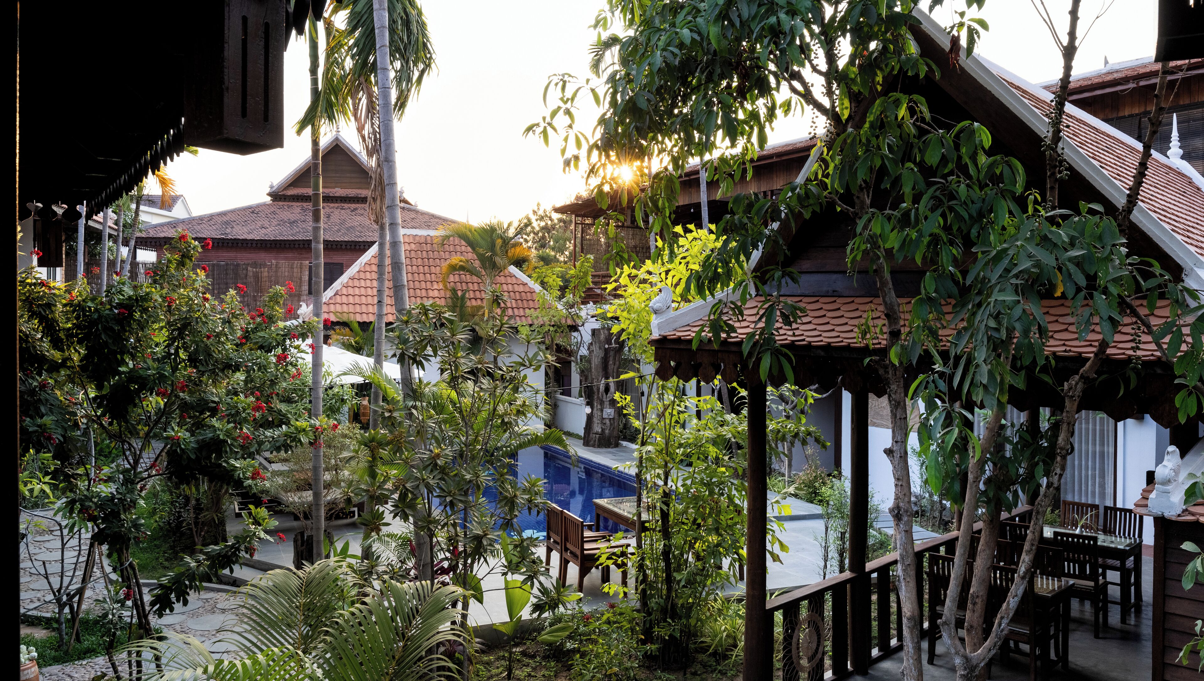 A traditional wooden structure with a tiled roof, surrounded by lush greenery and a small pool area.