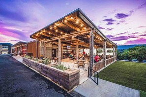 Un bâtiment moderne doté d’un patio couvert, d’un espace extérieur aménagé pour s’asseoir et d’un jardin paysager.