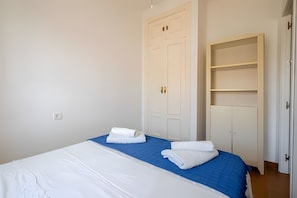 A bedroom with a bed, two white doors, and a wardrobe.