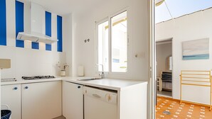 Eine moderne Küche mit weißen Schränken, einem Gasherd, einem Geschirrspüler und einem Fenster.