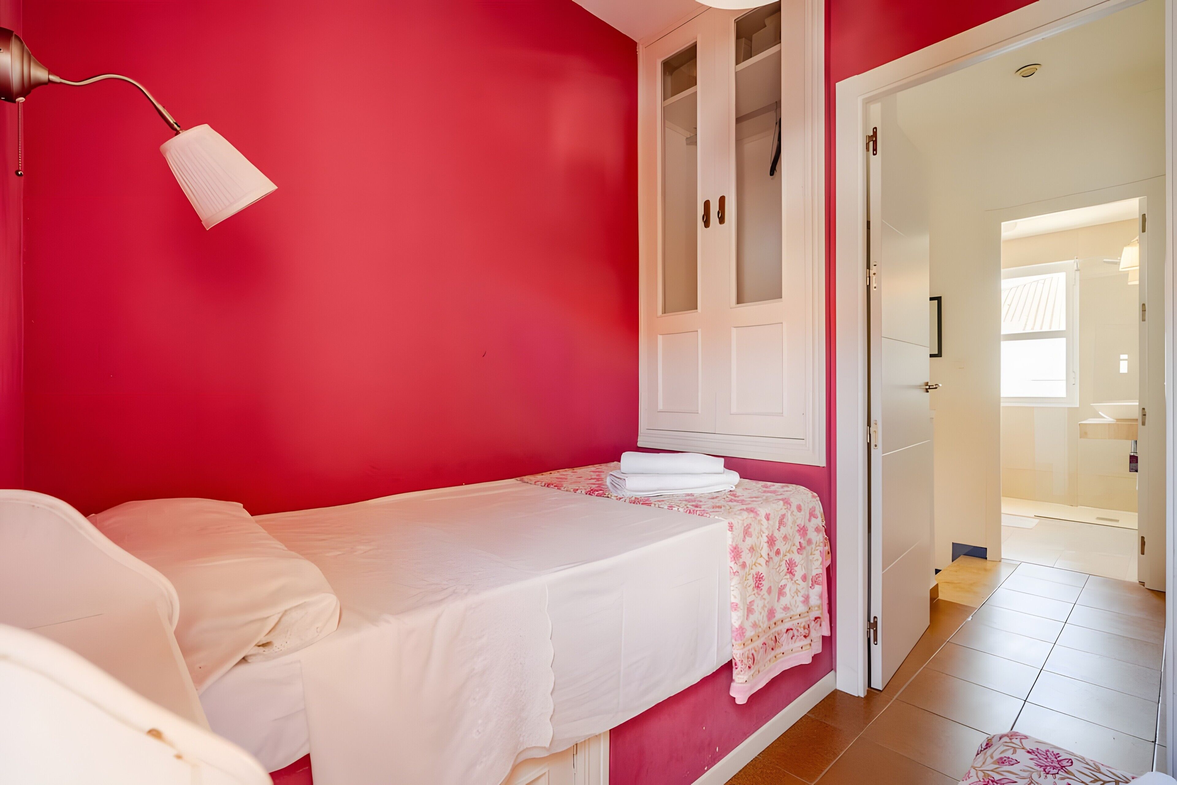 Ein Schlafzimmer mit Bett, Nachttisch, Kleiderschrank und einer Tür zu einem anderen Raum.