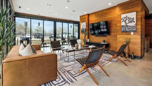 A modern interior with a large window, a flat-screen TV, and a seating area with chairs and a sofa. - South Lamar Condo / Sauna / Cold Plunge / Pickleball (Austin)